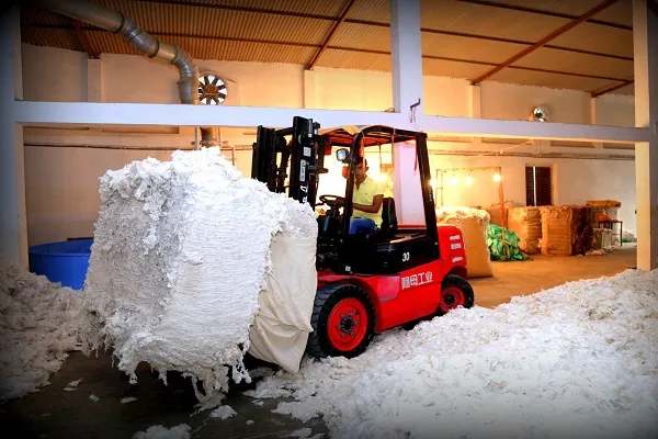 Karotoa Green cotton warehouse with forklift transporting raw cotton bales inside spinning mill facility.