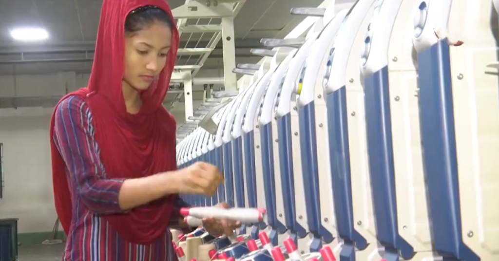 Female textile worker operating spinning machine at Karotoa Green production facility.